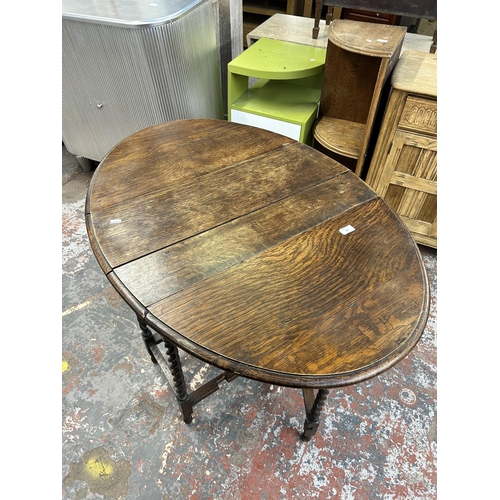 134 - An early 20th century oak drop leaf gate legged oval occasional table on barley twist supports - app... 