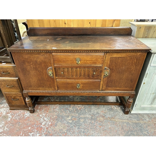 140 - An oak sideboard with three central drawers, two outer cupboard doors and baluster supports - approx... 