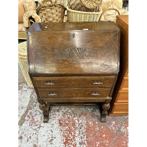 147 - An oak bureau with carved fall front, two drawers and baluster supports - approx. 101cm high x 72cm ... 