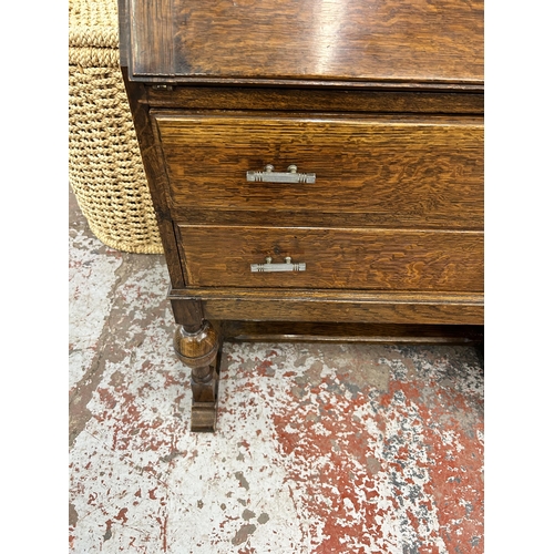 147 - An oak bureau with carved fall front, two drawers and baluster supports - approx. 101cm high x 72cm ... 