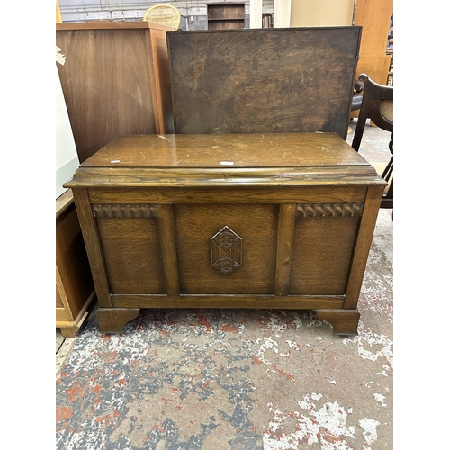 150 - An oak blanket box with carved three panel front - approx. 65cm high x 93cm wide x 47cm deep