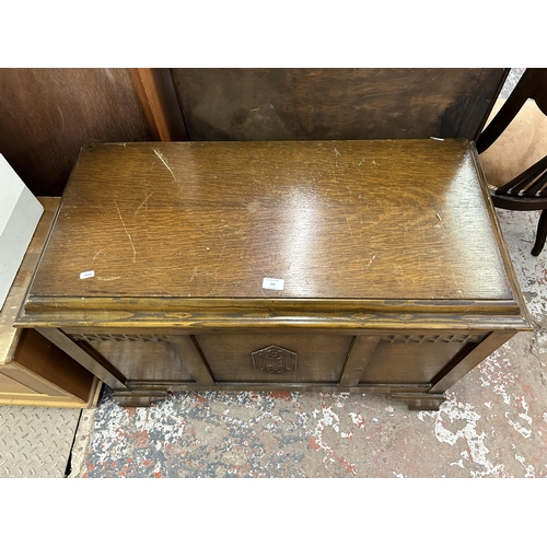 150 - An oak blanket box with carved three panel front - approx. 65cm high x 93cm wide x 47cm deep