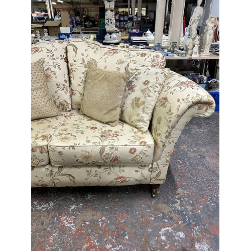 160 - A Regency style floral upholstered two seater sofa with mahogany supports and brass castors - approx... 