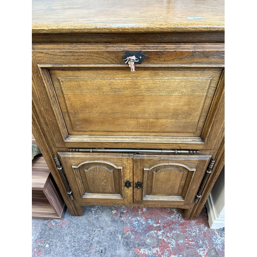 36 - A late 20th century oak cabinet with fall front and two lower cupboard doors - approx. 121cm high x ... 