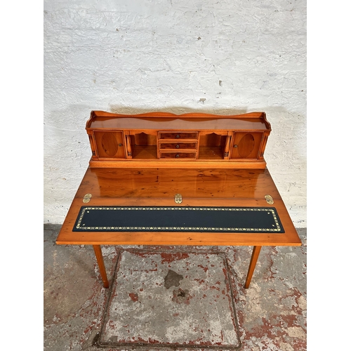 41 - A Regency style yew wood effect writing desk with folding blue leather writing surface, four long dr... 