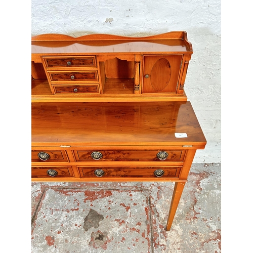 41 - A Regency style yew wood effect writing desk with folding blue leather writing surface, four long dr... 