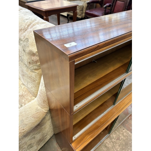 44 - A Minty walnut three tier bookcase with six glass sliding doors - approx. 109cm high x 89cm wide x 2... 