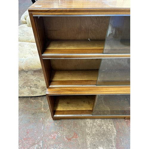 44 - A Minty walnut three tier bookcase with six glass sliding doors - approx. 109cm high x 89cm wide x 2... 