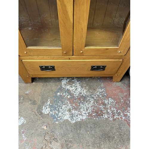 48 - A modern oak display cabinet with two glazed doors, four internal shelves and lower drawer - approx.... 