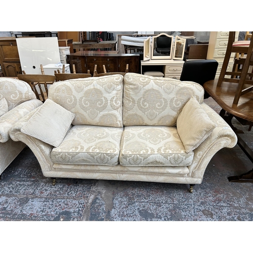 57 - A Regency style floral upholstered two piece lounge suite with mahogany supports and brass castors