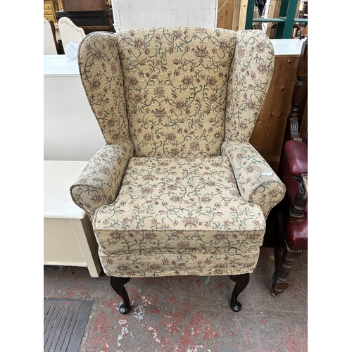 63 - A Victorian style floral upholstered wing back armchair with cabriole supports