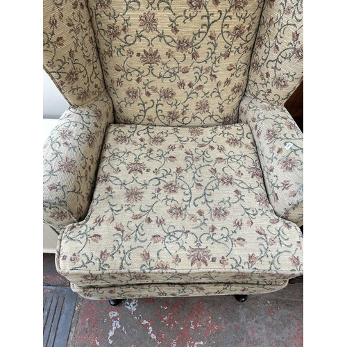 63 - A Victorian style floral upholstered wing back armchair with cabriole supports