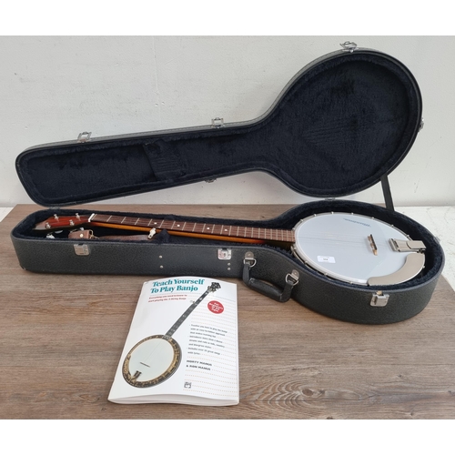 553 - A cased Musima five string banjo with tutorial book and accessories