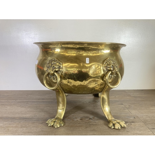 307 - A Victorian brass cauldron with lion paw supports and lion head design handles - approx. 37cm high x... 