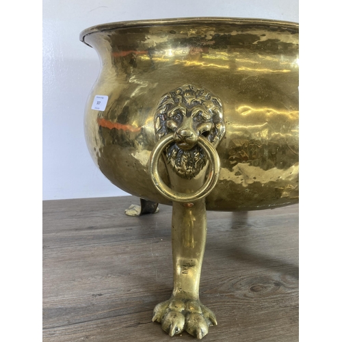 307 - A Victorian brass cauldron with lion paw supports and lion head design handles - approx. 37cm high x... 