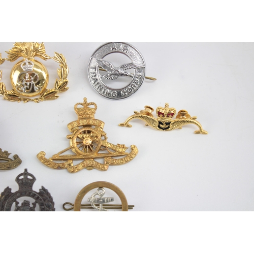 1253 - Twelve military cap badges to include Submariner, R.A Spinning Wheel etc.