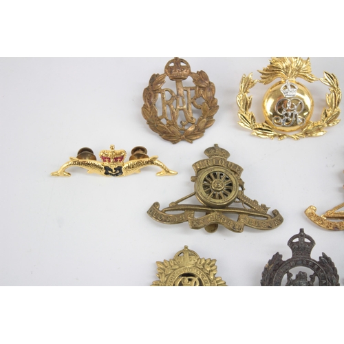 1253 - Twelve military cap badges to include Submariner, R.A Spinning Wheel etc.