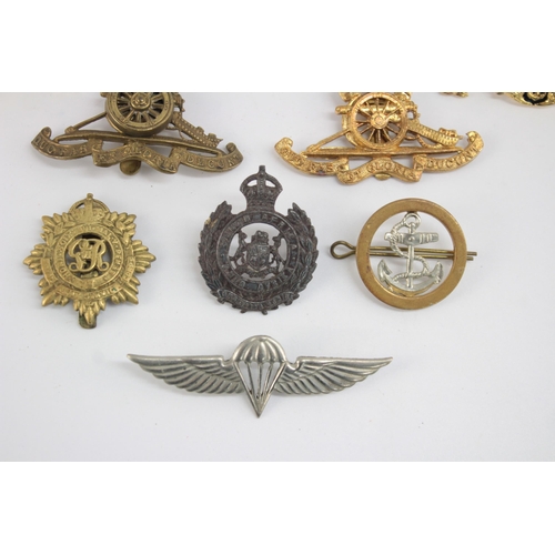 1253 - Twelve military cap badges to include Submariner, R.A Spinning Wheel etc.