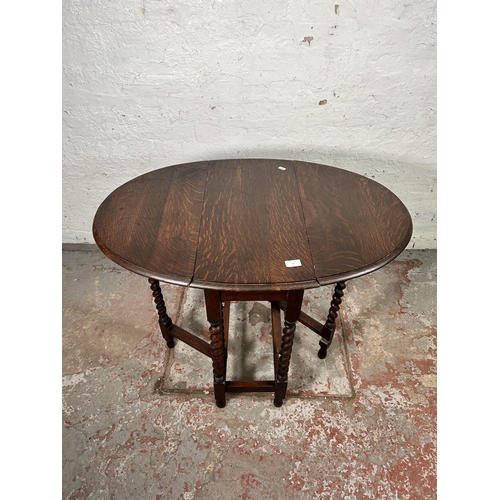 19 - An early 20th century oak drop leaf gate leg oval occasional table on barley twist supports - approx... 