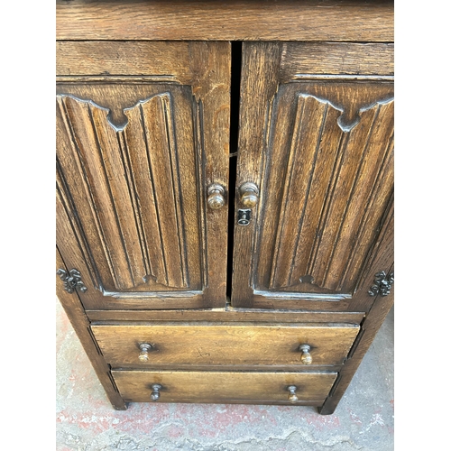 105 - A Goodalls of Manchester oak linenfold cabinet with two doors and two drawers  - approx. 116cm high ... 