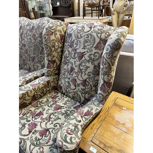 123 - A Georgian style floral upholstered wingback two piece lounge suite comprising three seater sofa and... 