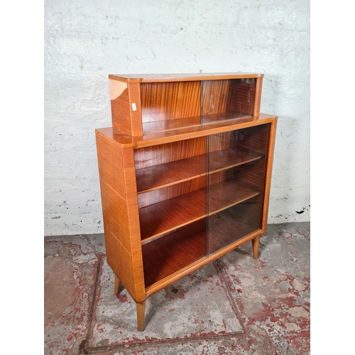 156 - A mid 20th century oak veneered four tier bookcase with four glass sliding doors and splayed support... 