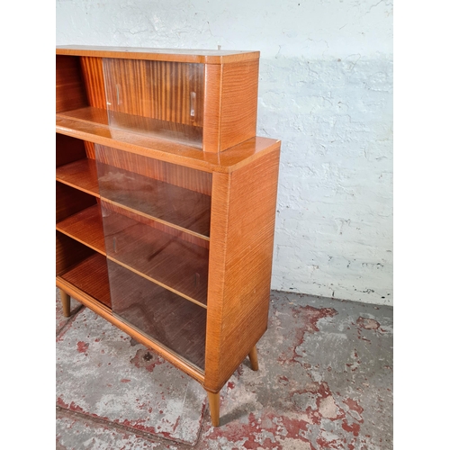 156 - A mid 20th century oak veneered four tier bookcase with four glass sliding doors and splayed support... 