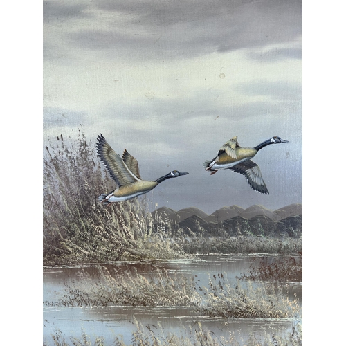 177 - A gilt framed oil on board of Canada geese in flight by H. Monahan - approx. 80cm high x 106cm wide