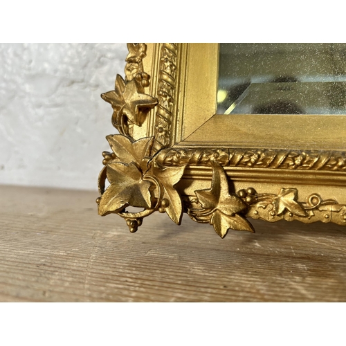 180 - A late 19th/early 20th century gilt framed bevelled edge wall mirror with foliate design - approx. 4... 