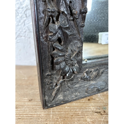 199 - A heavily carved oak framed wall mirror - approx. 44cm high x 34cm wide