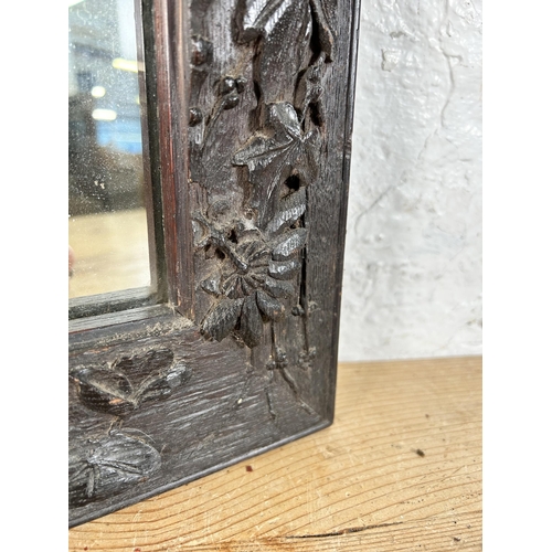 199 - A heavily carved oak framed wall mirror - approx. 44cm high x 34cm wide