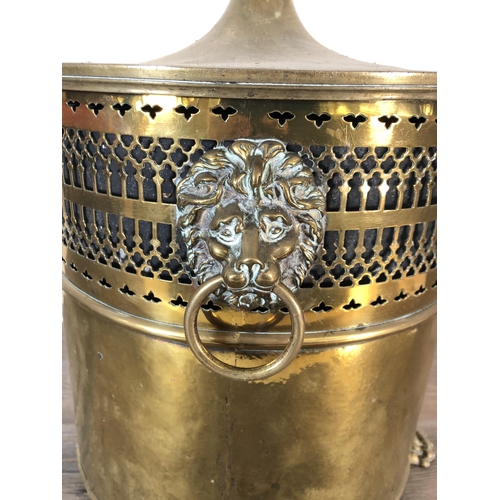 358 - A 19th century pierced brass lidded coal bucket with lion head handles, lion paw supports and acorn ... 