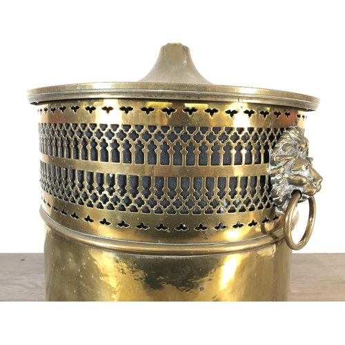 358 - A 19th century pierced brass lidded coal bucket with lion head handles, lion paw supports and acorn ... 