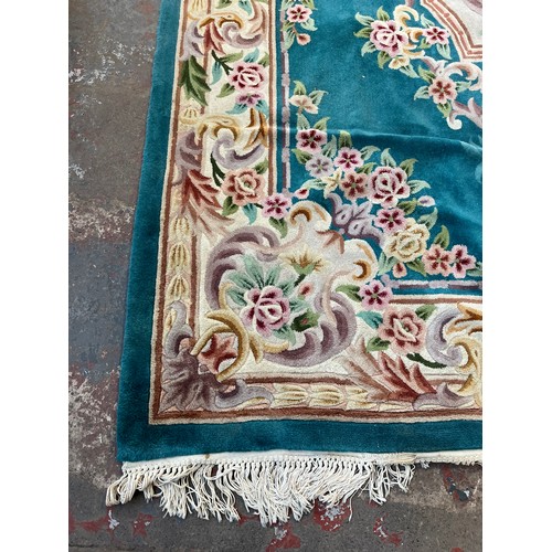 174 - A Chinese floral patterned wool rug - approx. 325cm x 215cm