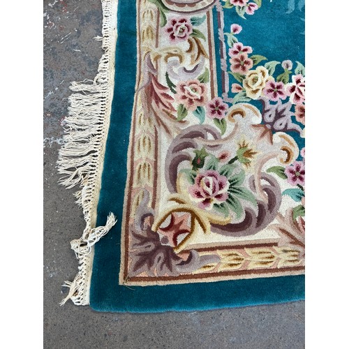 174 - A Chinese floral patterned wool rug - approx. 325cm x 215cm