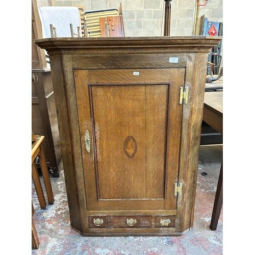 66 - A George III inlaid oak wall mountable corner cabinet with one lower drawer and brass 'H' hinges - a... 