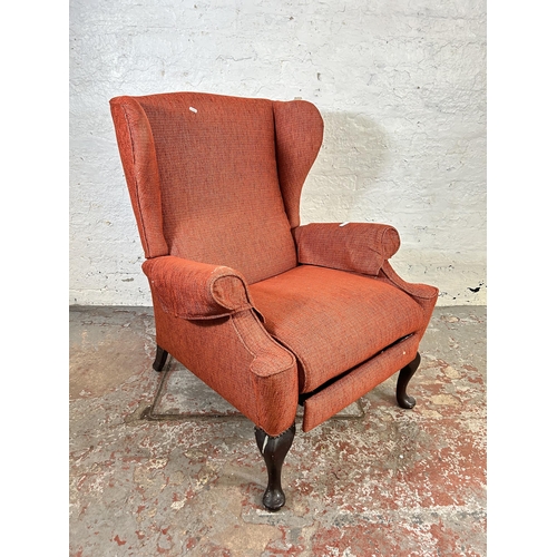 100 - A mid 20th century Parker Knoll PK 1102 red upholstered wing back armchair with later added foot res... 