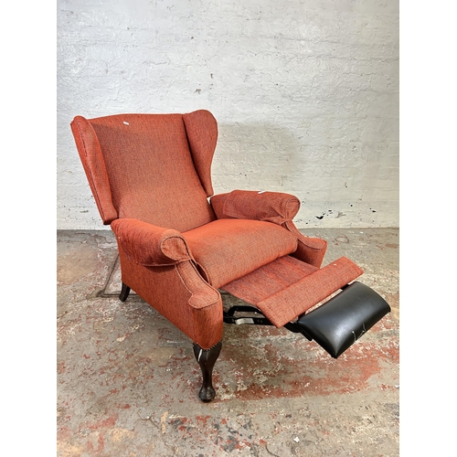 100 - A mid 20th century Parker Knoll PK 1102 red upholstered wing back armchair with later added foot res... 