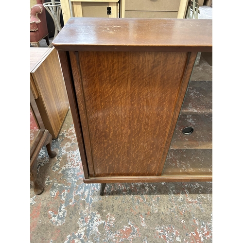 17 - A mid 20th century oak bookcase with two glass sliding doors and splayed supports - approx. 84cm hig... 