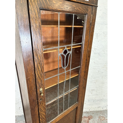 99 - An early 20th century oak display cabinet with single leaded and stained glass door and five interna... 