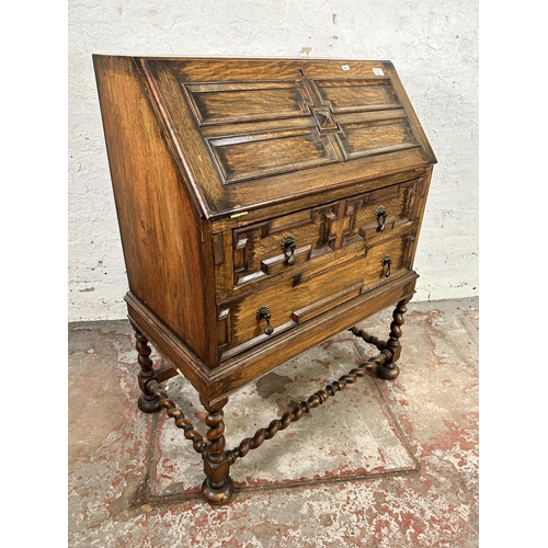 31 - A Jacobean style geometric carved oak bureau with fall front, two drawers and barley twist supports ... 