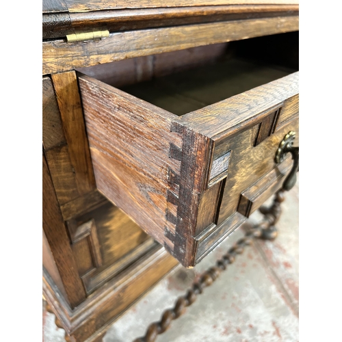 31 - A Jacobean style geometric carved oak bureau with fall front, two drawers and barley twist supports ... 