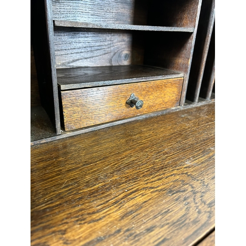 31 - A Jacobean style geometric carved oak bureau with fall front, two drawers and barley twist supports ... 