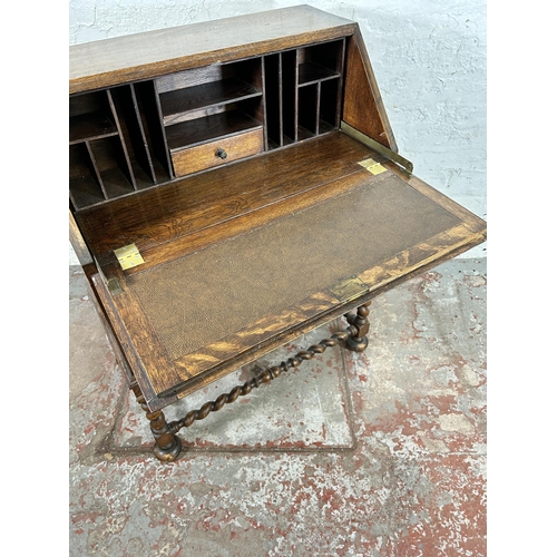 31 - A Jacobean style geometric carved oak bureau with fall front, two drawers and barley twist supports ... 