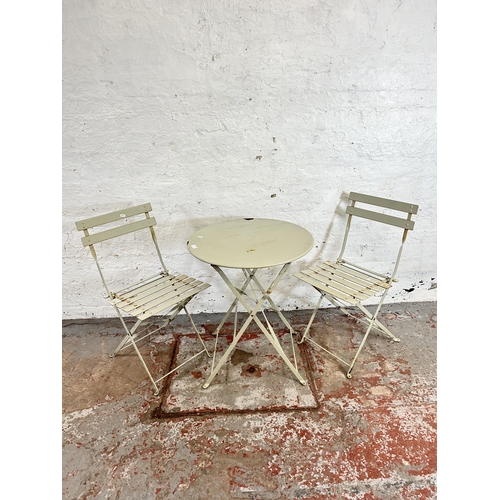 68A - A painted metal three piece outdoor dining suite comprising two folding chairs and one circular fold... 