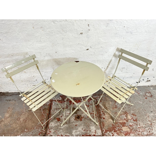 68A - A painted metal three piece outdoor dining suite comprising two folding chairs and one circular fold... 