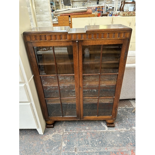 126 - A Harrops of Manchester oak bookcase with two glazed doors and baluster supports - approx. 123cm hig... 