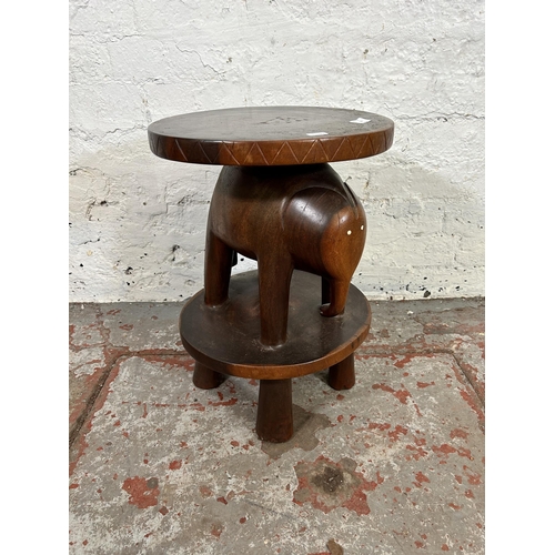 129 - A modern carved hardwood two tier circular side table with elephant design - approx. 50cm high x 36c... 