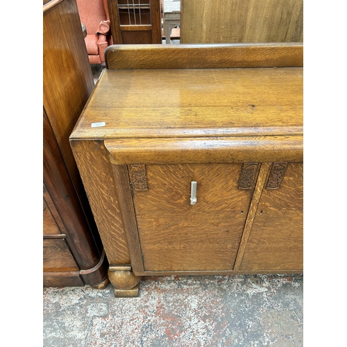 135A - An Art Deco oak sideboard with three cupboard doors, four internal drawers and baluster supports - a... 