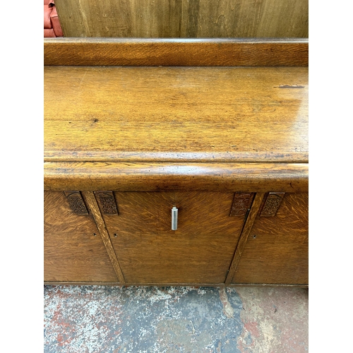 135A - An Art Deco oak sideboard with three cupboard doors, four internal drawers and baluster supports - a... 